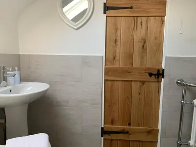 a bathroom with a sink and a wooden door at Bell Cottage in Mildenhall