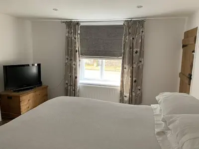 a bedroom with a bed and a tv and a window at Bell Cottage in Mildenhall