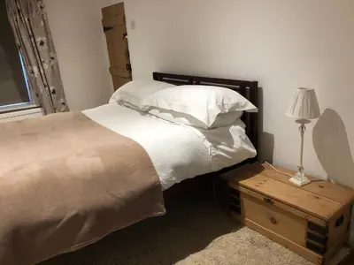 a bedroom with a bed and a table with a lamp at Bell Cottage in Mildenhall