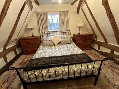 a bedroom with a bed with two dressers and a window at Beautiful Cottage opposite Hedingham Castle! in Castle Hedingham