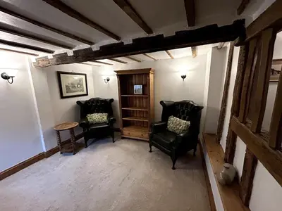 a living room with two chairs and a table at Beautiful Cottage opposite Hedingham Castle! in Castle Hedingham