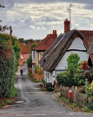 a house with a thatched roof on a village street at Beautiful Cottage opposite Hedingham Castle! in Castle Hedingham