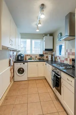 a kitchen with white cabinets and a washer and dryer at Pass the Keys Seaside Escape 2-Bedroom Flat EastBeach sleeps 4 in Southend-on-Sea