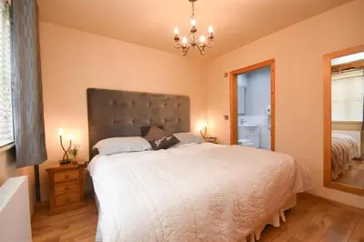 a bedroom with a large bed and a chandelier at The Barn in Little Maplestead