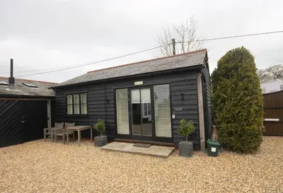 a small black tiny house with a table and plants at The Barn in Little Maplestead