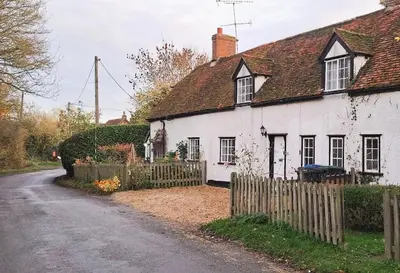 a white house with a fence next to a road at The Walnut Nook in Abbess Roding