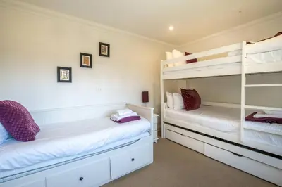 two bunk beds in a room with white walls at 7 Sanctuary Court - sleeps 12 - Thorpeness - Aldeburgh Coastal Cottages - Close to the Beach, Golf and the Country Club in Thorpeness