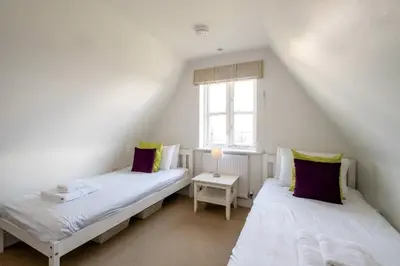 two twin beds in a room with a window at 7 Sanctuary Court - sleeps 12 - Thorpeness - Aldeburgh Coastal Cottages - Close to the Beach, Golf and the Country Club in Thorpeness