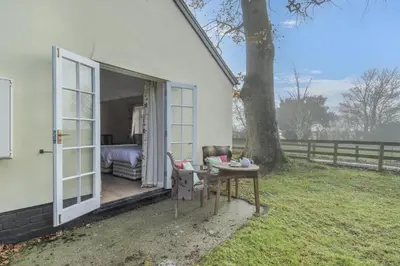 a white house with a bedroom and a table and a tree at 2 Bed in Bressingham oc-f33646 in Bressingham