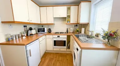 a kitchen with white cabinets and white appliances at Charming Willow Cottage in historic Grantchester in Barton