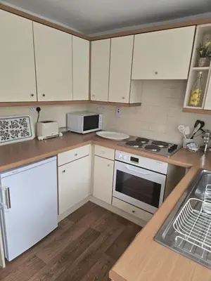 a kitchen with white cabinets and a stove top oven at Charming Willow Cottage in historic Grantchester in Barton