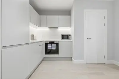 a white kitchen with white cabinets and a microwave at Heart of Brentwood - 1 Bed - Underground Parking - Fast Wifi in Brentwood