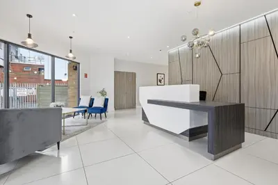 a living room with a table and blue chairs at Heart of Brentwood - 1 Bed - Underground Parking - Fast Wifi in Brentwood