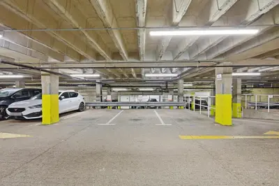 a parking garage with two cars parked in it at Heart of Brentwood - 1 Bed - Underground Parking - Fast Wifi in Brentwood