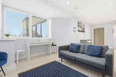 a living room with a couch and a table at Heart of Brentwood - 1 Bed - Underground Parking - Fast Wifi in Brentwood