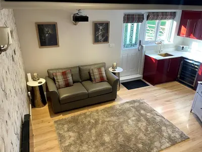 a living room with a couch and a kitchen at Greenfinch Lodge