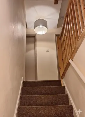 a staircase leading to a hallway with a door and a light fixture at Modern 4BR Cambridge House with Parking for 9 guests in Cambridge