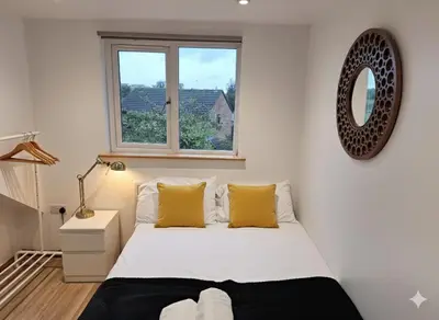 a bedroom with a bed with yellow pillows and a window at Modern 4BR Cambridge House with Parking for 9 guests in Cambridge