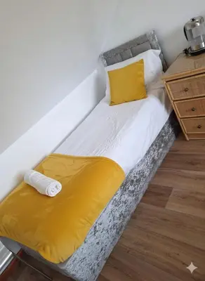 a bed with a yellow blanket on top of it at Modern 4BR Cambridge House with Parking for 9 guests in Cambridge