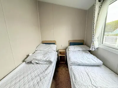 two beds in a small room with a window at Spacious 8 Berth Caravan With Decking At Naze Marine In Essex Ref 17012Rd in Walton-on-the-Naze
