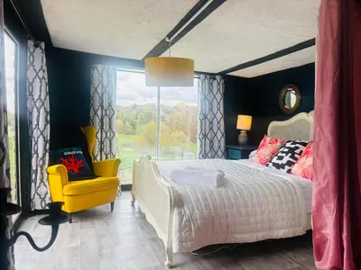 a bedroom with a bed and a yellow chair at Outlook farm cabin firepit in Hertford