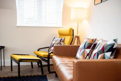a living room with a couch and yellow chairs at 5 The Royal Serviced Apartments Harwich, Private Parking, Fast Wifi in Parkeston