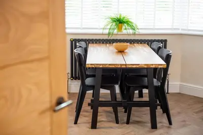 a wooden table with black chairs and a plant on top at 5 The Royal Serviced Apartments Harwich, Private Parking, Fast Wifi in Parkeston
