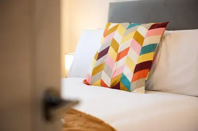 a bed with a colorful pillow sitting on a bed with at 5 The Royal Serviced Apartments Harwich, Private Parking, Fast Wifi in Parkeston