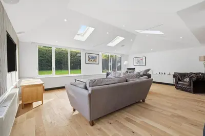 a living room with a couch and some windows at Four Bed House by Brookland Stays Serviced Accommodation Short Lets Brentwood with Free WiFi