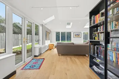 a living room with a couch and bookshelves at Four Bed House by Brookland Stays Serviced Accommodation Short Lets Brentwood with Free WiFi
