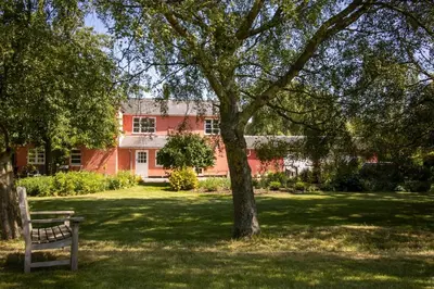 a park bench under a tree in front of a building at The Manor Dairy in Sandy
