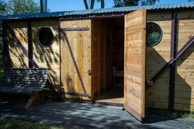 a wooden outhouse with a door on a deck at The Manor Dairy in Sandy