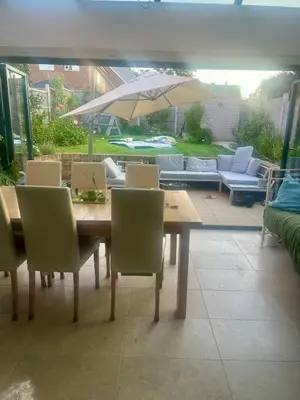 a wooden table with chairs and an umbrella on a patio at The Pink House in Lavenham