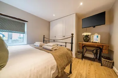 a bedroom with a bed with a tv on the wall at Bridewell Lane, Bury St Edmunds, Suffolk in Bury Saint Edmunds