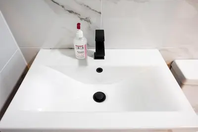 a white bathroom sink with a bottle of soap on it at 3 The Royal Serviced Apartments, Harwich -Ground Floor-Parking -Wifi in Parkeston