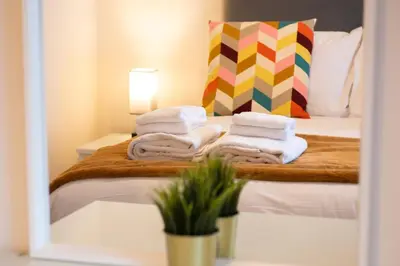 a room with a bed with towels and a pillow at 3 The Royal Serviced Apartments, Harwich -Ground Floor-Parking -Wifi in Parkeston