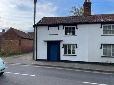 a white house with a blue door on a street at Central Grade 2 listed cottage in Attleborough