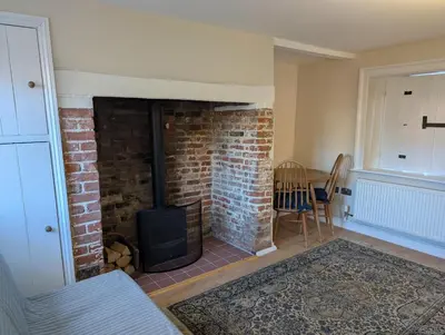 a brick fireplace in a living room with a stove at Central Grade 2 listed cottage in Attleborough