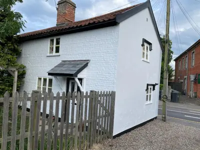 a small white house with a wooden fence at Central Grade 2 listed cottage in Attleborough