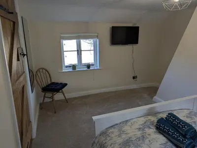a bedroom with a bed and a television and a chair at Central Grade 2 listed cottage in Attleborough