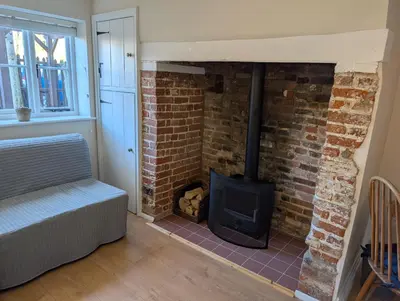 a brick fireplace in a living room with a couch at Central Grade 2 listed cottage in Attleborough