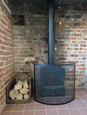a brick wall with a stove in a room at Central Grade 2 listed cottage in Attleborough