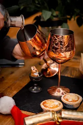 a person holding a wine glass on a table at Hollow Heath in Layer de la Haye