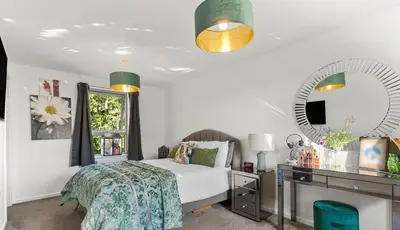 a bedroom with a bed and a desk and a mirror at Spacious 4 Bed house Perfect for Contractors-Relocators in Harlow