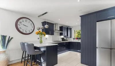 a kitchen with blue cabinets and a clock on the wall at Spacious 4 Bed house Perfect for Contractors-Relocators in Harlow
