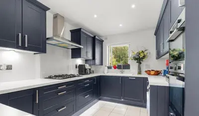 a kitchen with black cabinets and white counter tops at Spacious 4 Bed house Perfect for Contractors-Relocators in Harlow