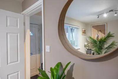 a hallway with a round mirror on a wall at Modern Comfort, Free Parking, Netflix & Disney plus in every Bedroom and Living Room in Shephall