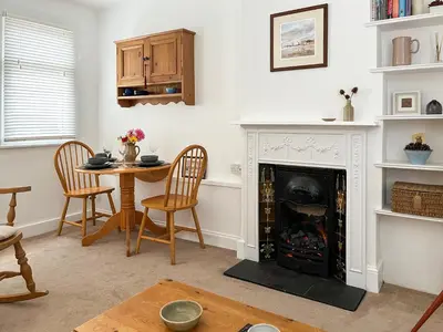 a living room with a fireplace and a table at Flock Cottage in Eye