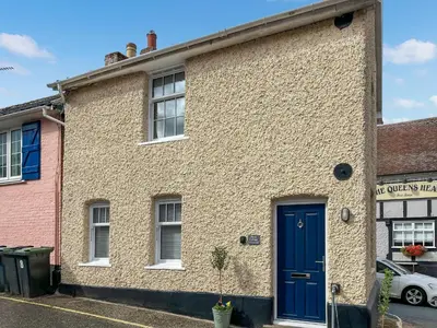 a brick house with a blue door on a street at Flock Cottage in Eye