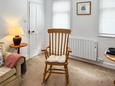 a rocking chair in a living room with a couch at Flock Cottage in Eye